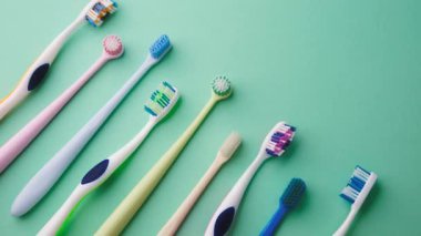 Nane yeşili arka planda çapraz dizilmiş renkli diş fırçaları koleksiyonu, temiz hijyen nesneleri.