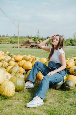 Balkabağı tarlasında oturan kadın, güneşin tadını çıkarıyor, sonbahar hasadı, balkabağı