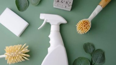 Yeşil bir yüzeye yerleştirilmiş temiz fırçalar ve süngerlerle dolu beyaz sprey şişesi..