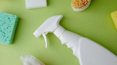 Yeşil bir yüzeyde ev temizliği için temiz sprey şişeleri ve süngerler..