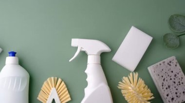 Yeşil arka planda ev temizliği için beyaz sprey, fırça ve süngerler..