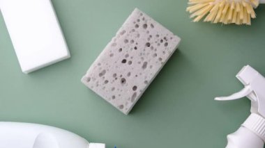 Evde bakım için pastel yeşil bir yüzeye temizleme malzemeleri, süngerler ve sprey şişesi.