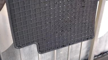 Siyah kauçuk araç zemin koruyucusu kurumaya bırakılmış, kirli su damlacıklarıyla kaplı ve desenli bir şebeke deseni var..