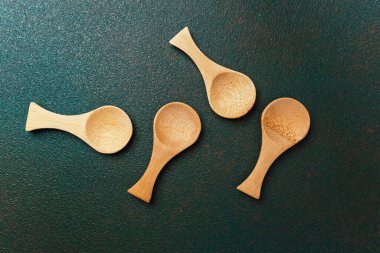 Birkaç küçük tahta kaşık düzgün bir şekilde koyu dokulu bir yüzeye dizilmiştir..