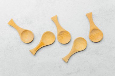 Beş el yapımı ahşap kaşık pürüzsüz bir ışık yüzeyinde güzelce sergilenir..