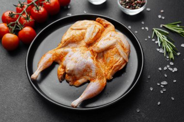 Siyah tabakta marine edilmiş bıldırcın, domates, otlar ve baharatlar.