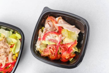 Yemek hazırlama ya da sağlıklı yemek hazırlama konsepti için içinde gurme malzemelerinin bulunduğu siyah kaplarda çeşitli taze salatalar.