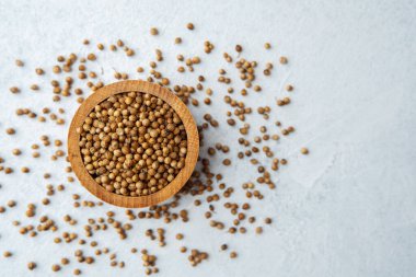 Beyaz arka planda kişniş tohumları olan ahşap kase.