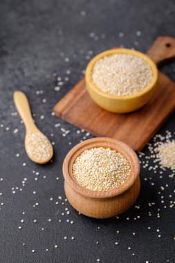 Çoklu tahta kaselerde kinoa tohumları ve karanlık arka planda kaşıklar.