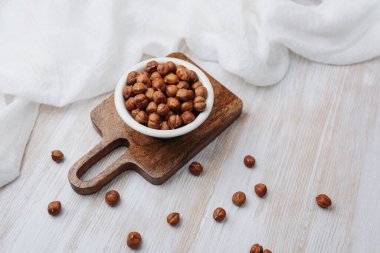 Tahtayı keserken fındıklar açık ahşap arka planda beyaz bez kullanılmış.