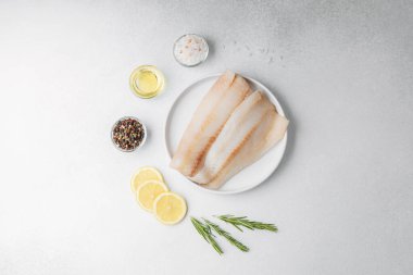 Beyaz arka planda limonlu ve biberiyeli ham pollock fileto.