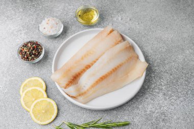 Gri arka planda baharat içeren ham pollock fileto.