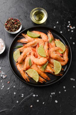 Pişirme malzemesi ya da menü tasarım konsepti için kara taş zemin üzerinde bitki ve deniz tuzu ile karides yemeği