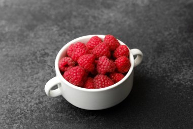 Meyve tatlısı için siyah arka planda beyaz kasede ahududu ya da temiz yemek kabı