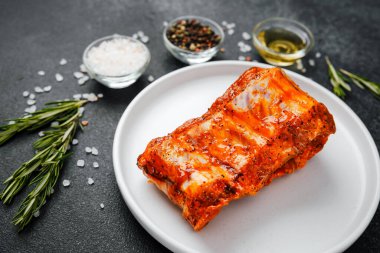 Beyaz tabakta marine edilmiş domuz pirzolası ve baharat.