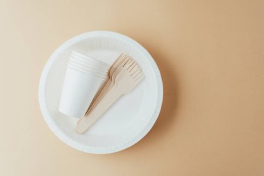 Bej arka planda ahşap çatalları olan tek kullanımlık beyaz masa takımı