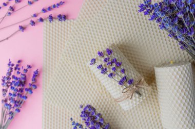 Balmumu mumlar ve pembe arka planda lavanta demetleri