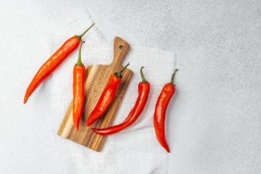 Ahşap bir tahtaya dizilmiş parlak kırmızı biberler pişirmeye hazır..