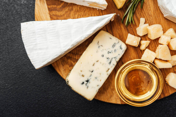 A selection of cheeses including brie and blue cheese accompanied by honey.