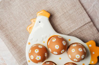 Beyaz papatya çiçekli Paskalya yumurtaları seramik tavuk tepsisinde.