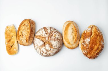 Temiz bir arkaplanda beş farklı taze ekmek sergilenir..