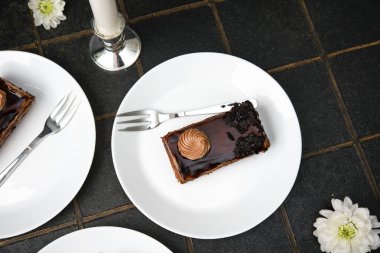 Çatal ve çiçek garnitürlü bozuk çikolatalı kek dilimi.