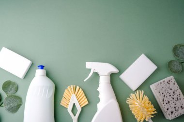 Yeşil arka plan görünümlü beyaz temizlik şişeleri fırçalar ve süngerler