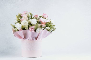 Pembe bir kapta sunulan bir buket gül ve yeşillik..