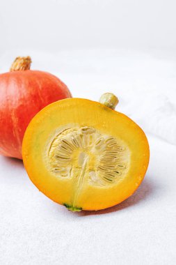 Portakal kabağı, tohumları ve hamuru gösteriyor. Beyaz kumaşın arka planında kabak var.