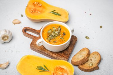 Kabak çekirdekli kabak çorbası ve sarımsaklı ekmek dilimleme tahtasıyla servis edilen tost.