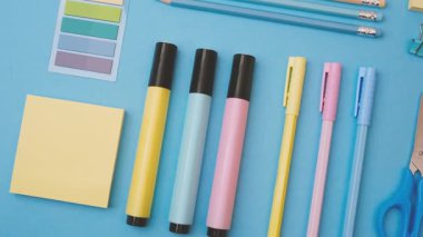 Renkli kalemler, kalemler ve parlak mavi arka plan masasına yerleştirilmiş yapışkan notlar..