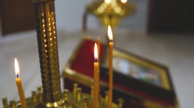 Dini simge ve kitabın yanındaki altın şamdanda mumlar yakıyor.