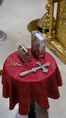 Kırmızı sunak bezinde kutsal eşyalar, süslü dini eşyalar ve altın sunak..