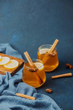 Limon dilimli sıcak içecekler, tarçın çubukları ve koyu mavi üzerinde yıldız anason.
