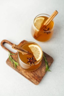 Tarçın çubuklu sıcak içecekler, limon dilimleri, yıldız anasonu ve ahşap biberiye filizi.