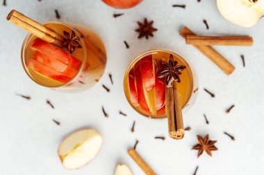 Tarçın çubuklu iki bardak elma şarabı, yıldız anason ve elma dilimleri..
