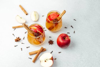 Tarçın çubukları, yıldız anason ve açık gri yüzeyde karanfilli elma şarabı..