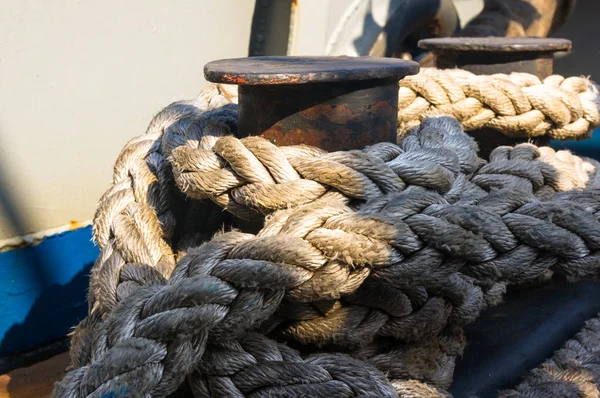 Old braided rope on the wooden deck of a sea boat, cleats, anchor mechanisms