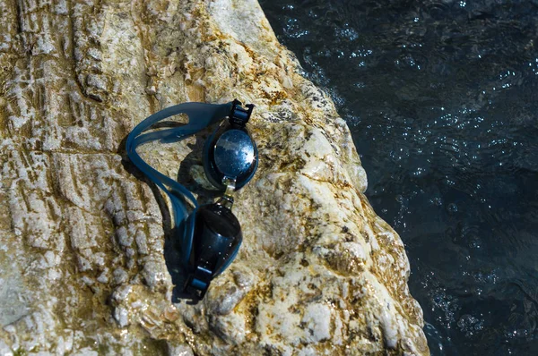 eyeglasses for swimming on a pebble beach in the sea waves, a warm summer day, close-up