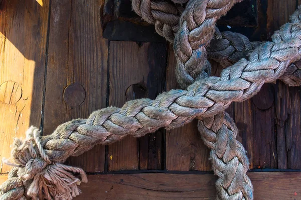 Old braided rope on the wooden deck of a sea boat, cleats, anchor mechanisms