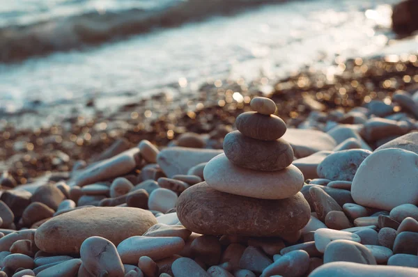 folded pyramid Zen pebble stones on the sea beach at sunset