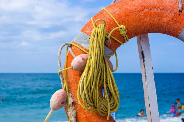 Orange emergency lifebuoy on a pebbly sea beach, close up