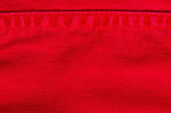 clothing items stonewashed red cotton fabric texture with seams, clasps, buttons and rivets, macro
