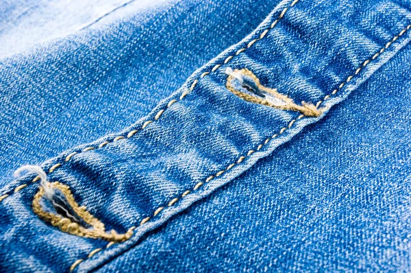 clothing items blue stonewashed faded jeans cotton fabric texture with seams, clasps, buttons and rivets, macro, close-up