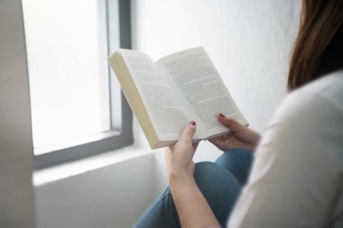 Evde kitap okuyan genç bir kadın..