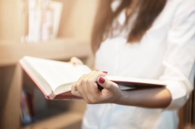 Genç kadın bir Kütüphanesi'nde kitap okuma.