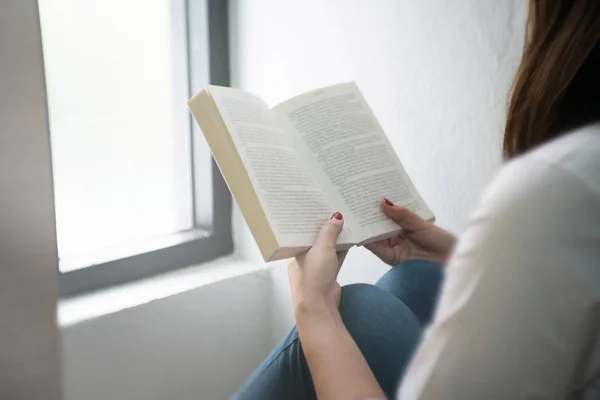 Evde kitap okuyan genç bir kadın..