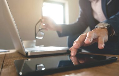 Dijital tablet ve mali iş stratejisi ile dizüstü bilgisayar ile bir işyerinde çalışan iş adamı