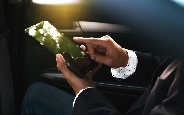 businessman working in a car and using a tablet