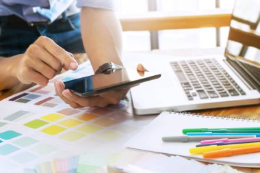 Tablet kullanma ve modern bir ofis masasında grafiklerde renk üzerinde yaratıcı iş adamı